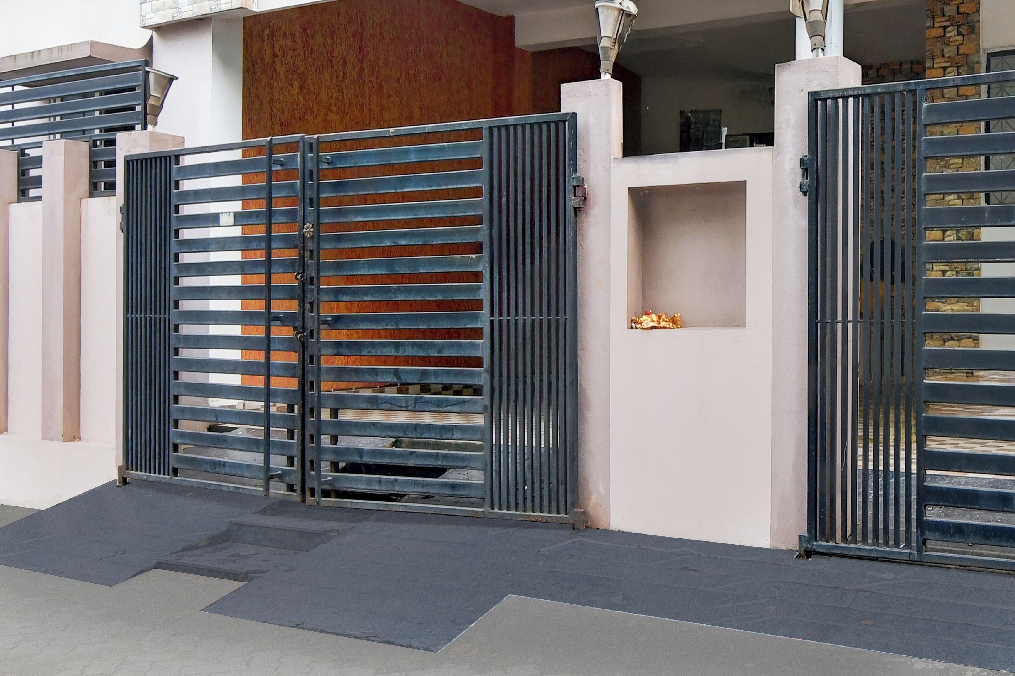 A gated entrance with a metal gate and a small shelf with decorative items.