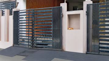 A gated entrance with a metal gate and a small shelf with decorative items.