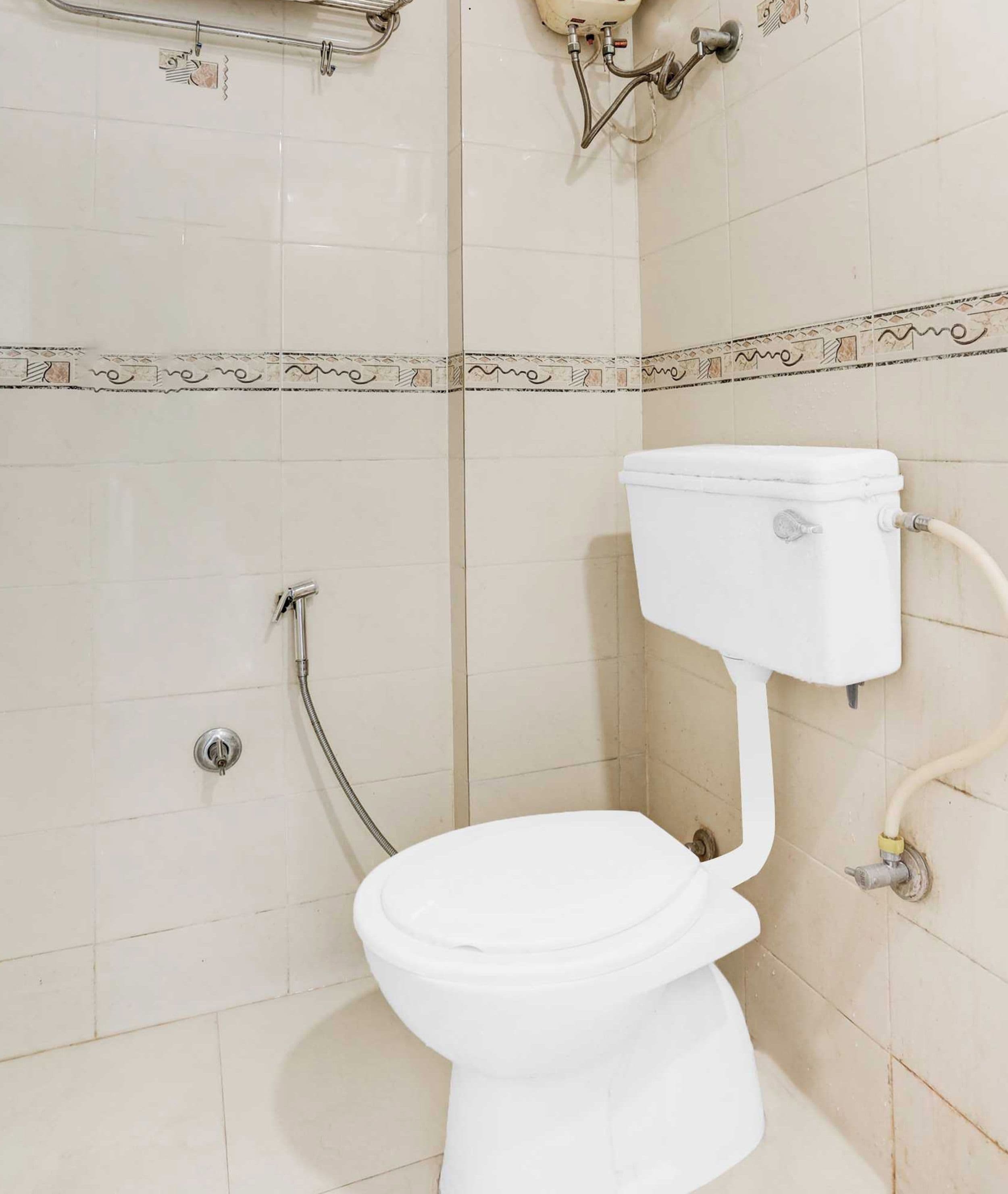 Sanitário branco com bidê, chuveiro e torneira embutida na parede.