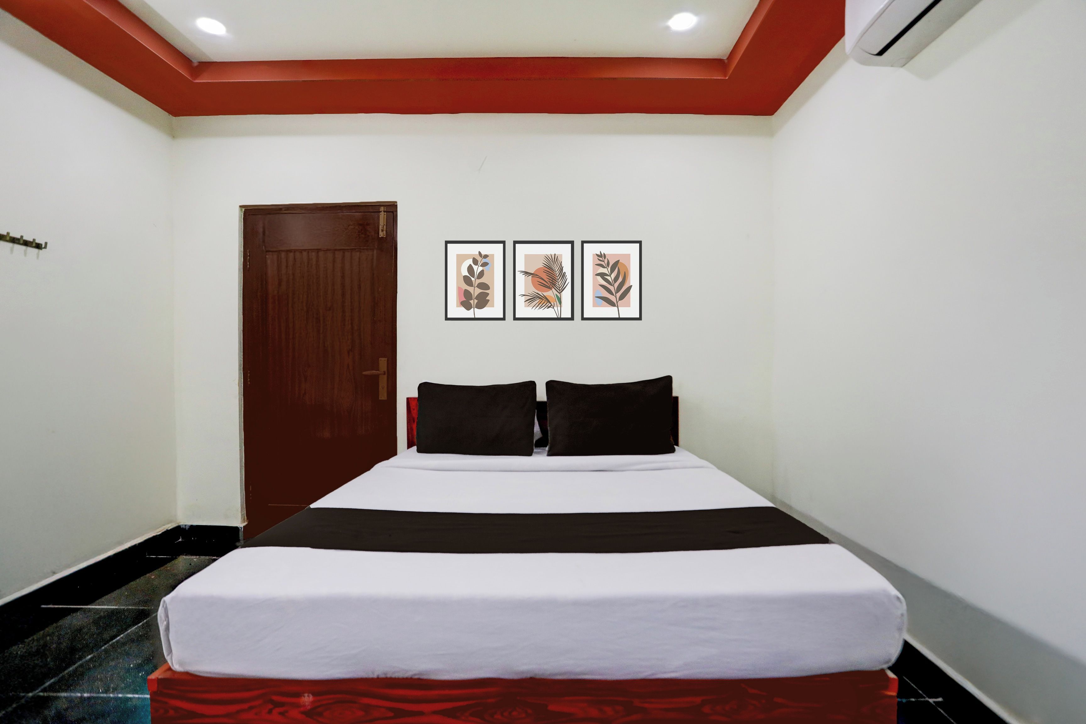 Una habitación de hotel con una cama, una puerta y tres cuadros enmarcados.