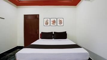 Una habitación de hotel con una cama, una puerta y tres cuadros enmarcados.