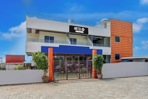 A modern hotel with a prominent sign, a gated entrance, and a clear sky.