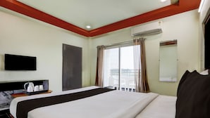 A hotel room with a bed, a flat-screen TV, an air conditioning unit, and a window with curtains. - Hotel O Chirala Beach View (Chirala)