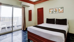 A hotel room with a bed, a sliding glass door to a balcony, and three framed artworks on the wall. - Hotel O Chirala Beach View (Chirala)