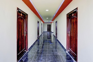 Un pasillo con puertas a ambos lados, suelo de baldosas e iluminación empotrada en el techo.