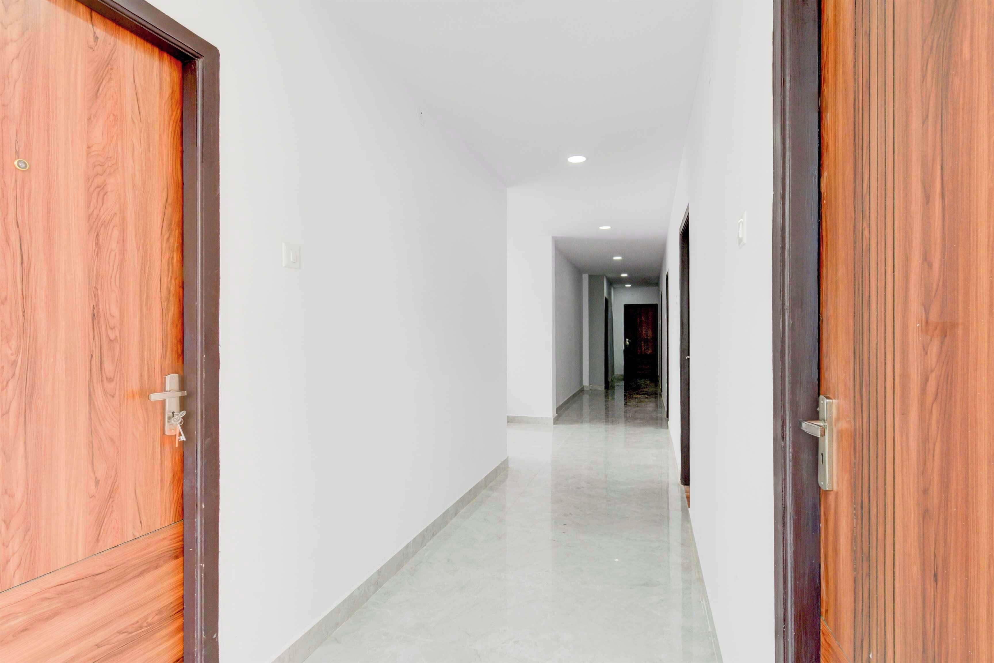 Un pasillo con puertas de madera a ambos lados, que conduce a una habitación con una cortina oscura.