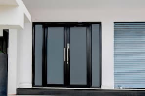 A black double door with a handle and a garage door with horizontal slats. - Townhouse Oak Townhouse Oak BN Reddy (Hyderabad)