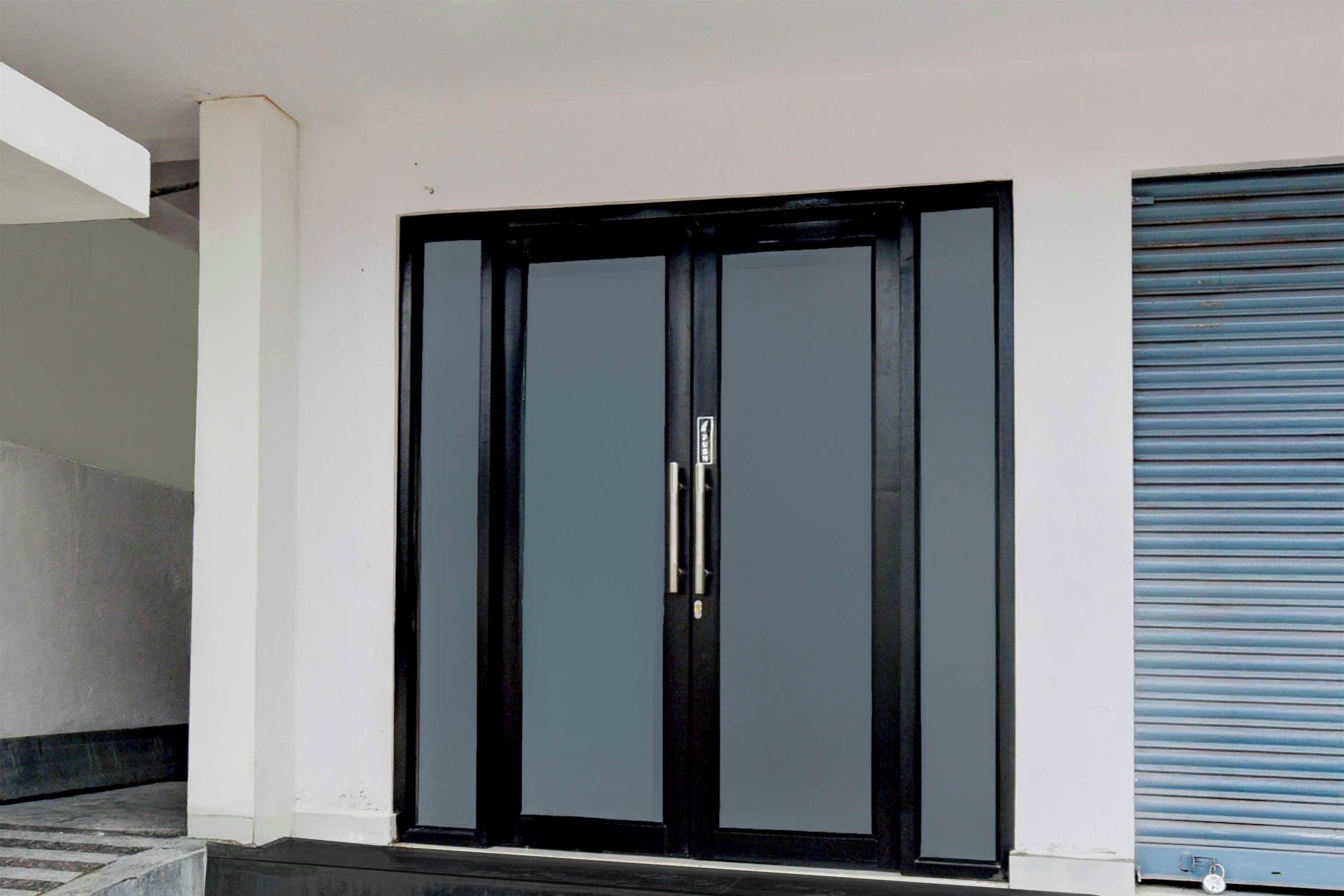 Puerta doble negra con manija, incrustada en una pared blanca con un persiano azul a la derecha.