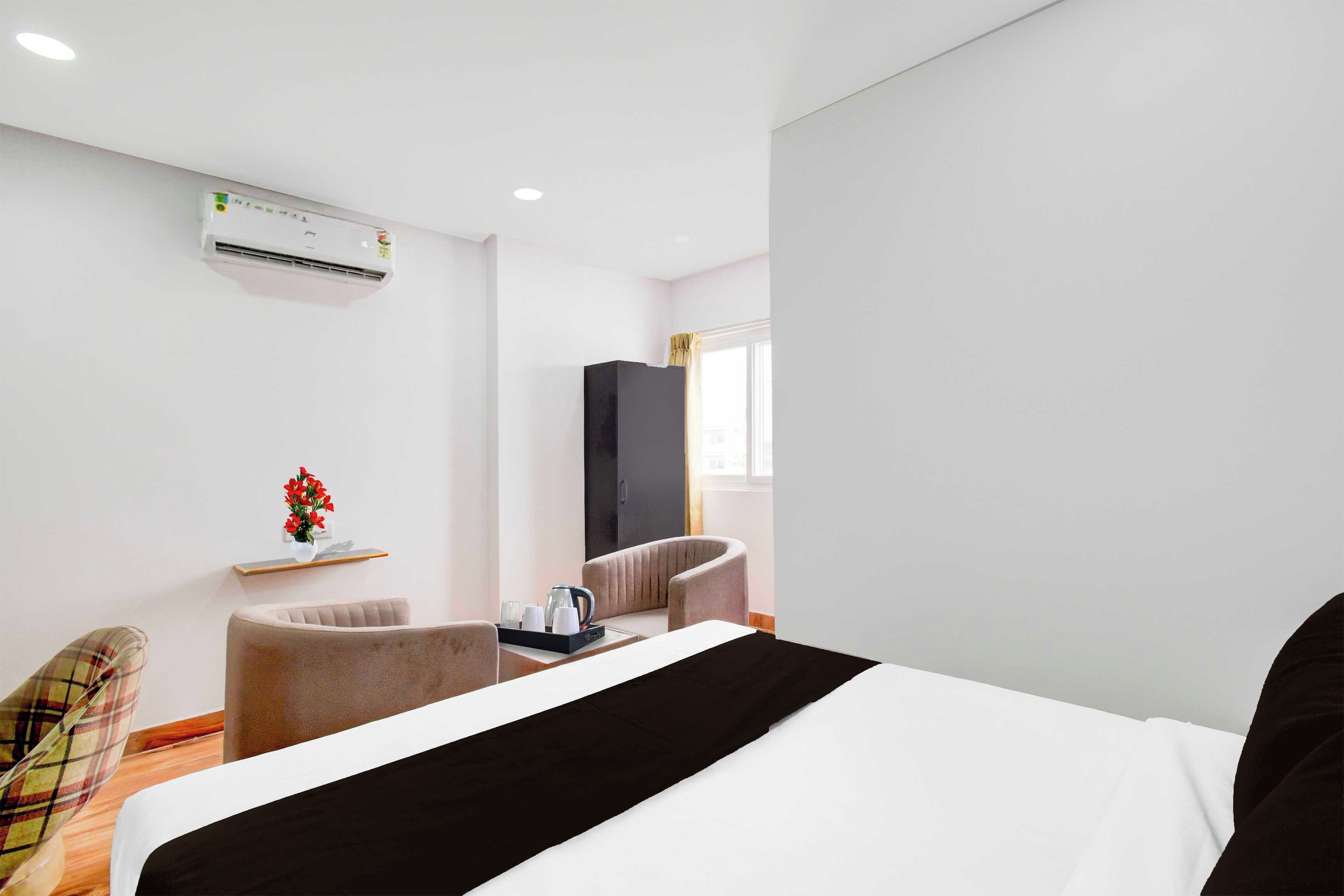 Una habitación de hotel con una cama, una silla, una mesita con una bandeja, aire acondicionado y una ventana con cortinas.
