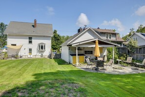 Een achtertuin met terras, een overdekte zithoek en een gazon.