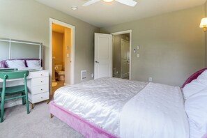 Ein Schlafzimmer mit einem Bett, einem Schreibtisch, einem Stuhl und einer Tür zu einem Badezimmer.