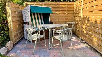 A patio area with a table and chairs, a covered seating area, and a wooden fence.