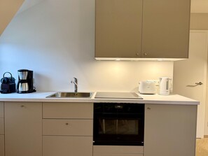 Eine moderne Küche mit eingebautem Backofen, einer Spüle und einer Kaffeemaschine.