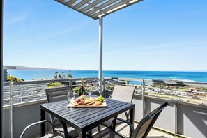 Un balcón con una mesa lista para una comida, con vista al mar.