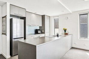 A modern kitchen with a central island, stainless steel appliances, and a view of the outdoors. - Oceanscapes - U15 Point Grey Lorne (Lorne)
