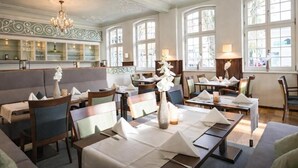 A restaurant with tables set for dining, a bar area, and large windows. - Hotel Fürstenhof (Bad Pyrmont)