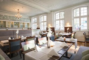 A restaurant with tables set for dining, a bar area, and large windows.