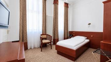Una camera d'albergo con un letto, una scrivania, una sedia e un armadio.