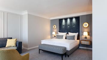A hotel room with a bed, bedside tables, a sofa, and a chair.