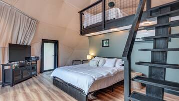 A bedroom with a bed, a TV, a desk, and a staircase.