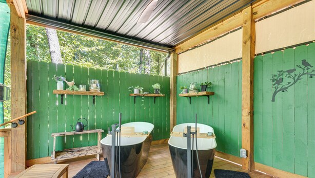 A wooden deck with two black hot tubs, wooden shelves with plants, and a green fence. - Hot Tub & 2 Fire Pits! Secluded Lyles Getaway (Lyles)