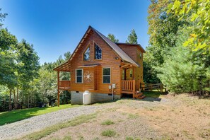 A wooden cabin with a porch, a compass, and a large water container outside. - 4 Mi to Cherokee Lake! Wooded Escape Near Hiking (Murphy)
