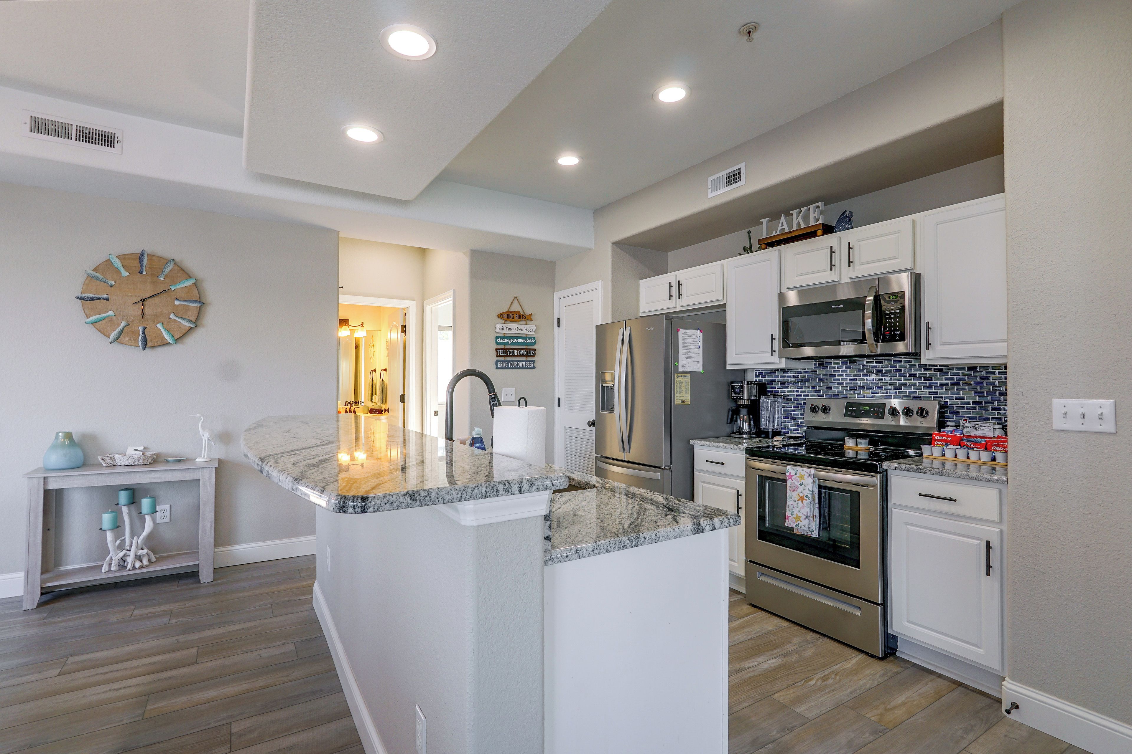 A modern kitchen with a central island, stainless steel appliances, and a decorative wall clock.