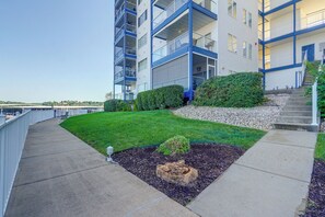 A modern multi-story building with balconies, a well-maintained lawn, and a clear sky. - Pool Access! Family Getaway on Lake of the Ozarks (Lake Ozark)