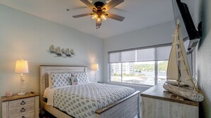 Una camera da letto con un letto, lampade da comodino, una ventola a soffitto, una decorazione a forma di barca a vela e una finestra con vista.