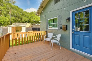 A wooden deck with two white chairs, a blue door, and a window with a view of trees. - South Tampa Stay w/ Backyard & Fire Pit! (Tampa)