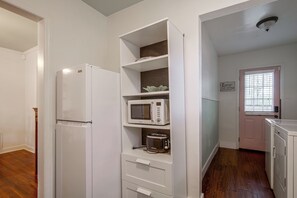 A compact kitchen with white appliances, including a refrigerator, microwave, and toaster, and a wooden floor. - East Memphis Duplex Near Midtown & Downtown (Memphis)