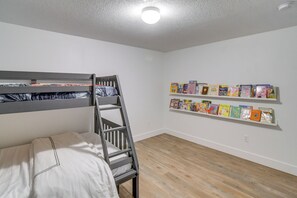 A room with a bunk bed, a ladder, and a bookshelf with children's books. - Game Nights + Family Fun! Modern Waukee Home (WDM)