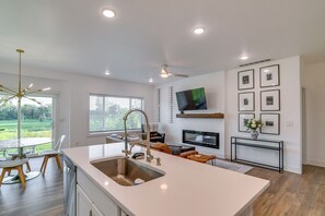 A modern kitchen with a large island, built-in appliances, and a dining area with a view. - Game Nights + Family Fun! Modern Waukee Home (WDM)