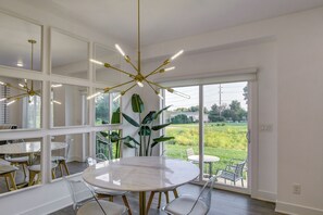A modern dining area with a round table, chairs, and a ceiling light fixture. - Game Nights + Family Fun! Modern Waukee Home (WDM)