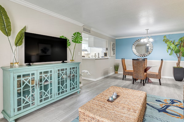 A living room with a television, a cabinet, and a dining area with chairs and a table.