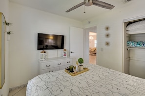 A bedroom with a bed, a television on the wall, a ceiling fan, and a door leading to another room. - Families w/ Pets! Home 10 Mi to Busch Gardens (Tampa)