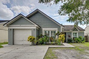 A residential house with a garage, a front yard with various plants, and a clear sky. - Families w/ Pets! Home 10 Mi to Busch Gardens (Tampa)