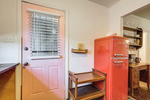 A pink door with a window, a wooden bench, and a red refrigerator with a coffee maker. - Near Midtown Attractions! Memphis Duplex (Memphis)
