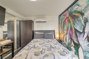 Una habitación de hotel con cama, armario y un cuadro grande en la pared.