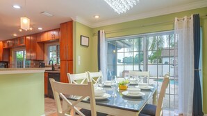 A modern kitchen with wooden cabinets and a dining area with a glass table and chairs. - Hot Tub, Water View! Largo Home 10 Mi to Beaches (Largo)