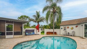 A swimming pool with a tiled edge, a covered seating area with a sofa and cushions, and a small deck with chairs. - Hot Tub, Water View! Largo Home 10 Mi to Beaches (Largo)