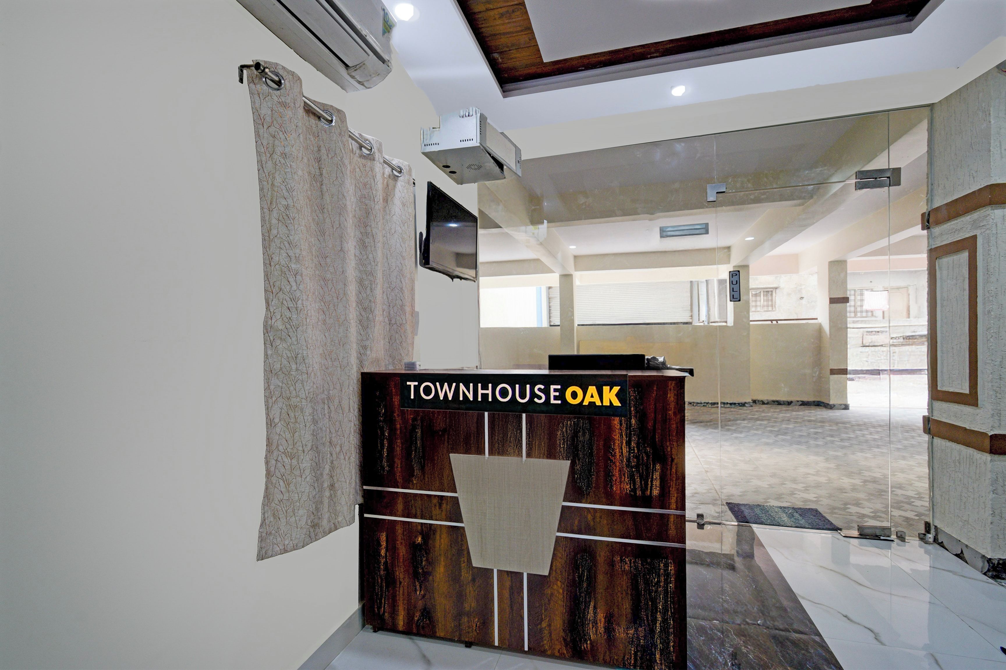 A reception desk with a sign reading 'TOWNHOUSE OAK' in a spacious lobby with a high ceiling and a large window.