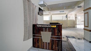 Uma receção com uma placa a indicar 'TOWNHOUSE OAK' num hall amplo com teto alto e uma janela grande.