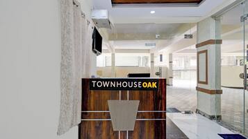 A reception desk with a sign reading 'TOWNHOUSE OAK' in a modern lobby with glass doors and a tiled floor.