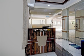 Un mostrador de recepción con un letrero que dice 'TOWNHOUSE OAK' en un vestíbulo moderno con puertas de vidrio y piso de baldosas.