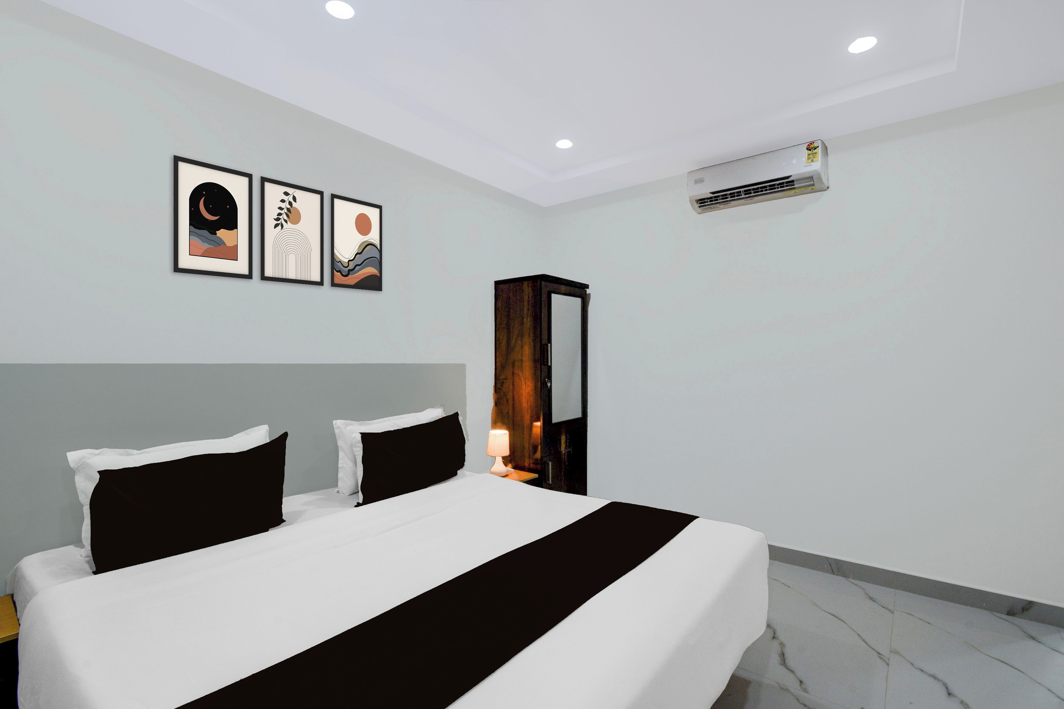 Una habitación de hotel con una cama, una mesita de noche, una lámpara y tres obras de arte enmarcadas en la pared.