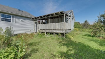 A two-story house with a wooden deck and a small porch.