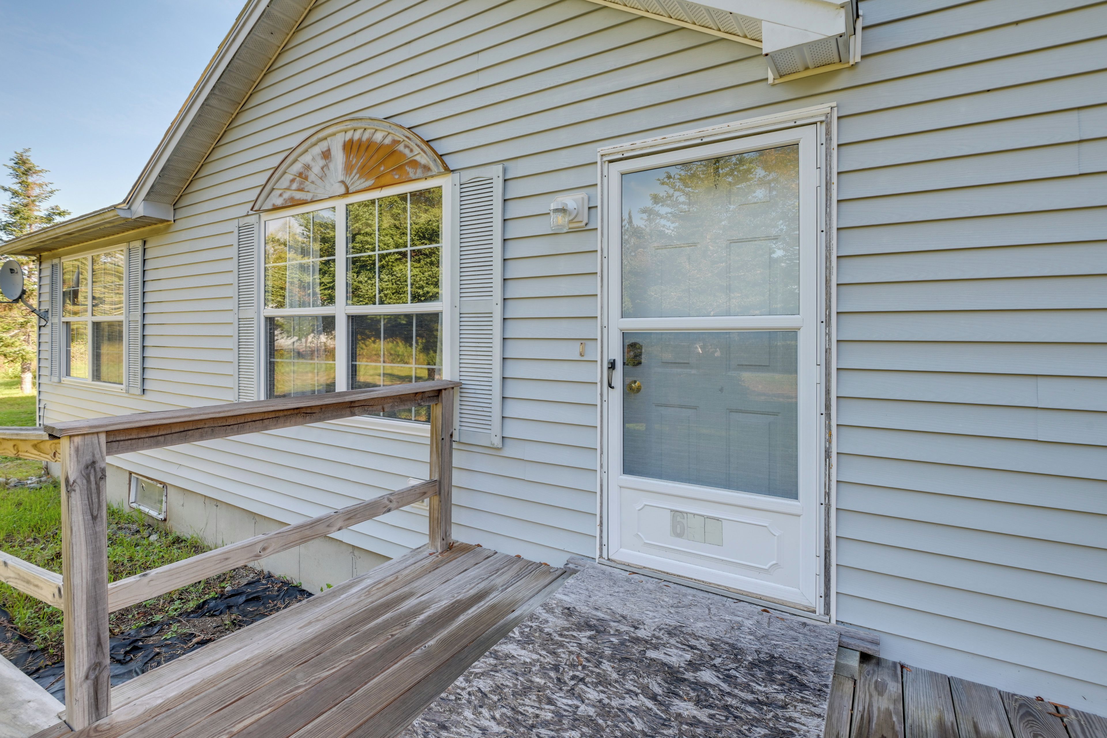 A house with a wooden deck, a garage door, and a front door with a glass panel.