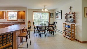 A kitchen with wooden cabinets, a dining table with chairs, a built-in bookshelf, and a window with a view of greenery. - 21 Acres, Near Trails to Shore with Island Access (Lubec)