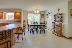 A kitchen with wooden cabinets, a dining table with chairs, a built-in bookshelf, and a window with a view of greenery. - 21 Acres, Near Trails to Shore with Island Access (Lubec)